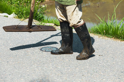 Low section of man wearing boots standing on road