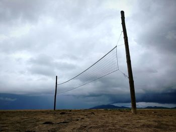 Low angle view of net on sand against sky