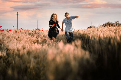 Women standing on field against sky during sunset