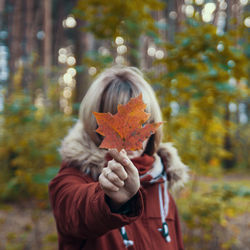 Portrait of woman holding orange leaf