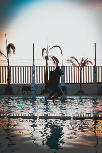 Woman in swimming pool by sea against sky