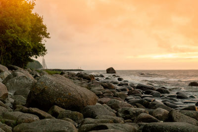 Rocks on beach against sky during sunset