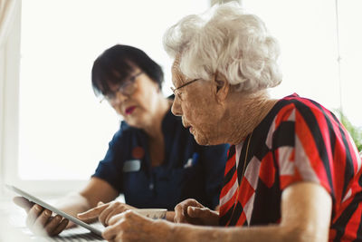 Senior woman using digital tablet with caretaker at home