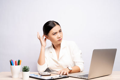 Young woman using mobile phone while sitting on table