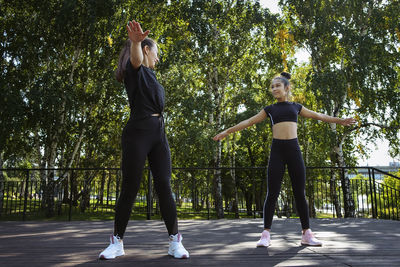 Girl in sportswear on a sunny summer day on the embankment in the park doing fitness and stretching