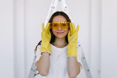 Portrait of a smiling woman painter designer in yellow safety glasses and gloves doing home repairs