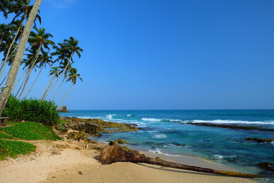 View of calm beach against clear blue sky