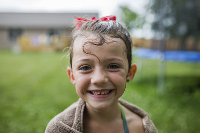 Portrait of happy girl wrapped in towel at yard