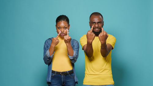 Portrait of couple gesturing while standing against wall