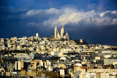 Buildings in city against cloudy sky