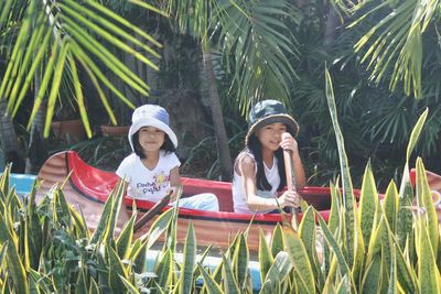 Portrait of girls sitting in kayak amidst grass