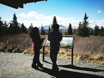 Rear view of people standing on landscape against sky