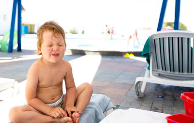 Small child in panama hat plays in the summer on sunny day near swimming pool