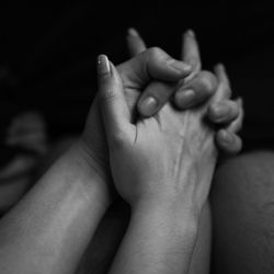 Cropped image of couple holding hands in darkroom