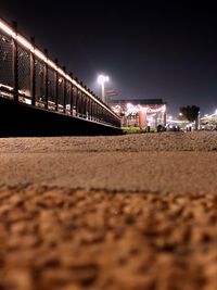 Surface level of illuminated street against sky at night