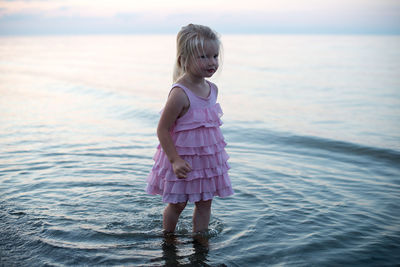 Girl standing in sea against sky