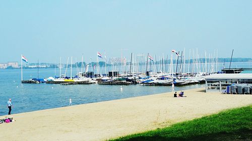 Sailboats moored on sea against clear sky