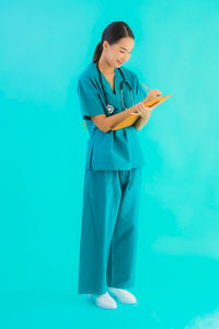 Full length of woman standing against blue background