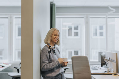 Smiling woman holding coffee cup in office