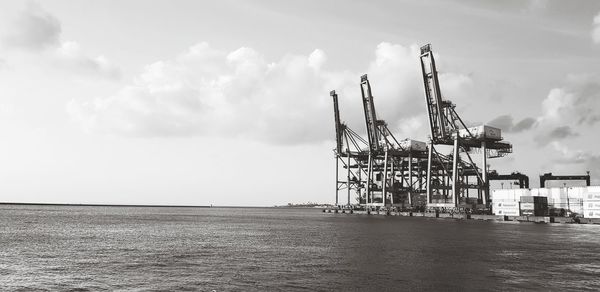 Cranes at commercial dock against sky