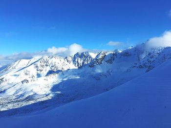 Snow covered landscape against blue sky