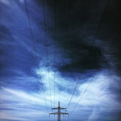 Low angle view of electricity pylon against blue sky