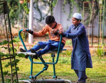 Boy assisting friend in exercising at park