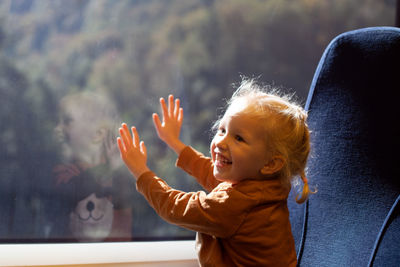 Cute smiling girl touching glass at train