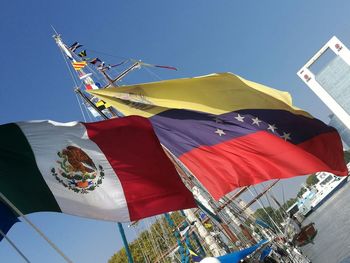 Low angle view of flags against clear blue sky