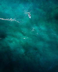 Aerial view of person surfing on surfboard in blue sea