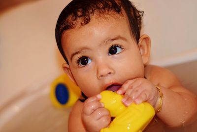 Close-up of cute baby girl playing with rubber duck while bathing in bathtub