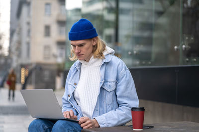 Young woman using laptop while sitting on table