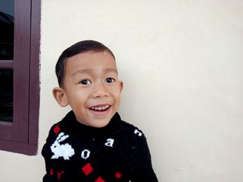 Portrait of smiling boy standing against wall