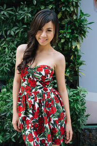 Portrait of young woman standing against plants