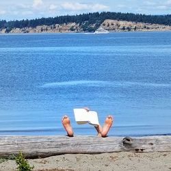 Man relaxing on beach against sky