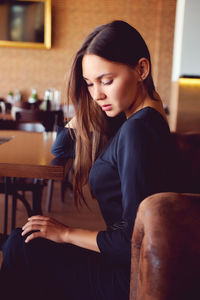 Young woman sitting against wall in restaurant