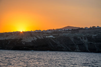 Mountain by sea against sky during sunset