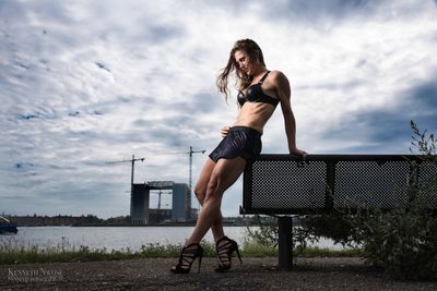 Full length of young woman standing against sky