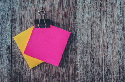 Close-up of adhesive notes and binder clip hanging on wood