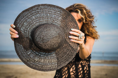 Woman holding hat at beach