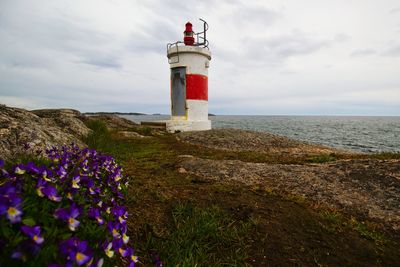 Lighthouse on beach against cloudy sky