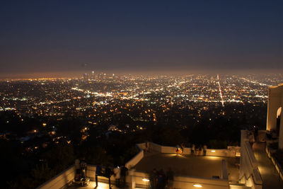 High angle view of illuminated city buildings against sky at night