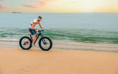 Young man riding a fat bike on the beach