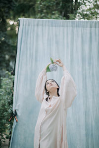 Woman holding umbrella standing against plants