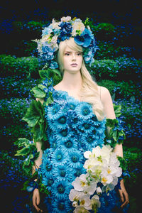 Portrait of woman standing by flowering plants