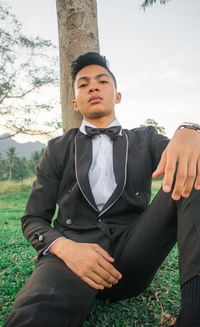 Full length of young man sitting on land