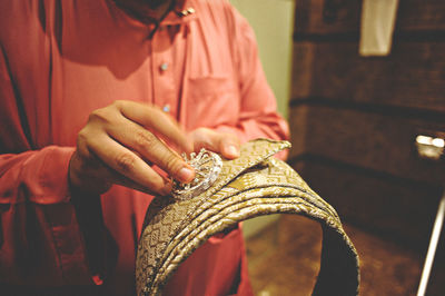 Midsection of woman attaching jewelry on fabric