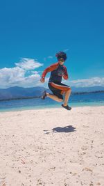 Woman jumping at beach against sky