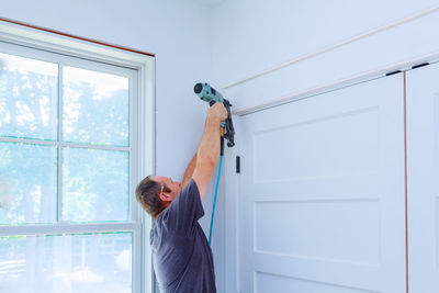 Man holding umbrella standing by window at home