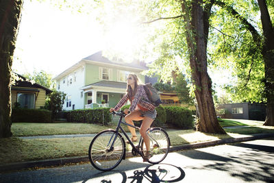 Full length of woman riding bicycle on street during summer